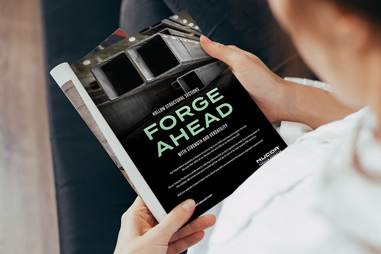 Closeup image of someone reading a Nucor Tubular ad that says, "Forge Ahead"